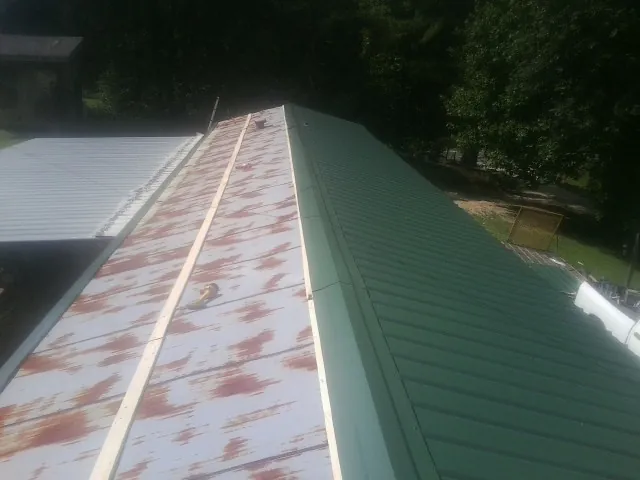 Old rusted panels beside newly installed green metal roofing — Wind Damage Roof Repair by Roofing Brothers in Buckingham
